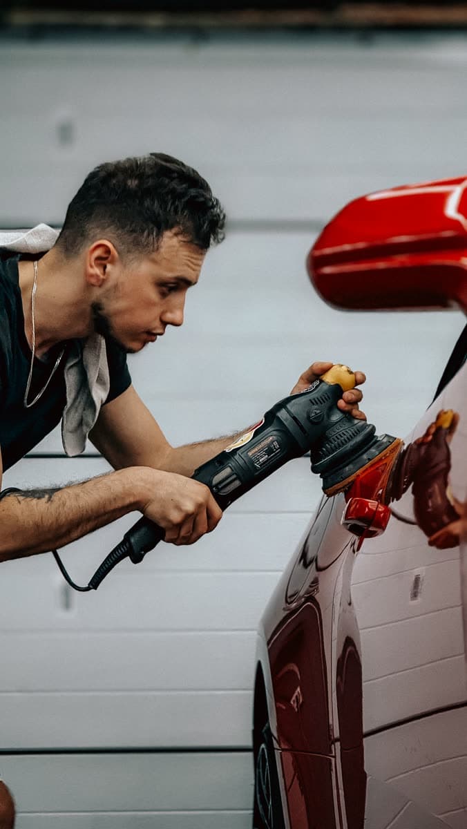 Machine polisher being worked across a car panel